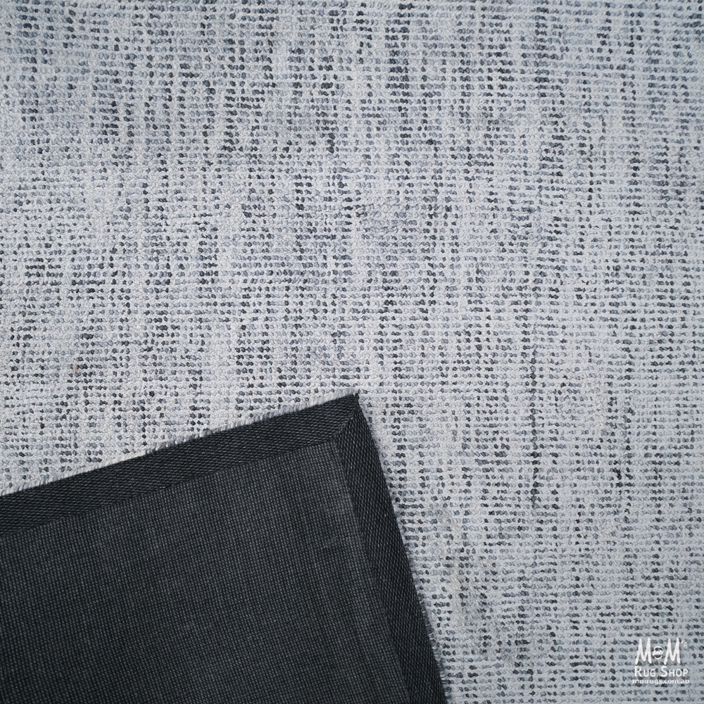 Close-up of a wool and viscose fabric named Toro Silver by India, showcasing its shiny, textured silver-gray surface.